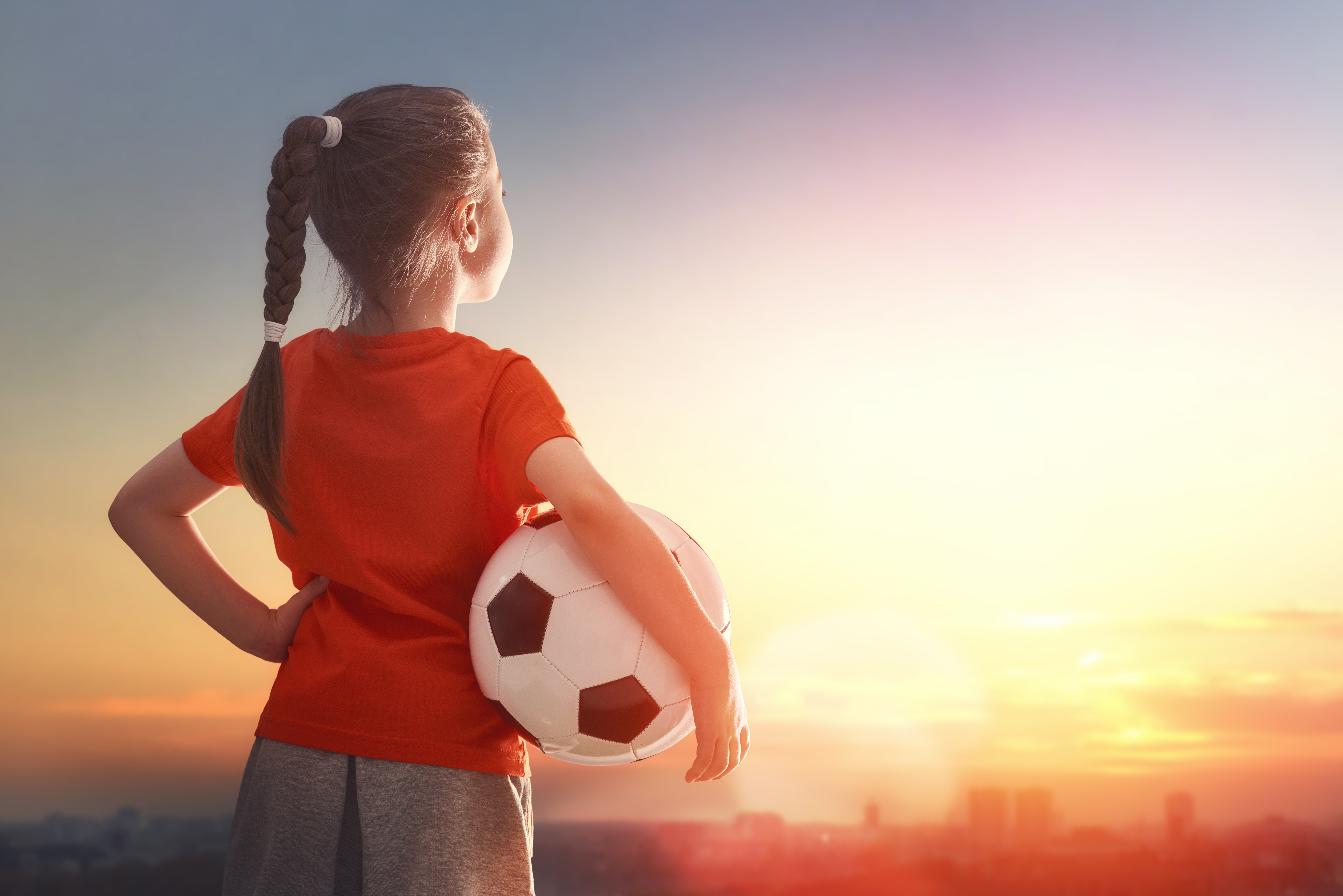 Young soccer player with ball at sunset